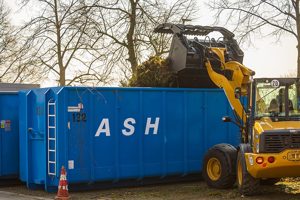 Ein Radlader befüllt einen Container mit Grünabfall