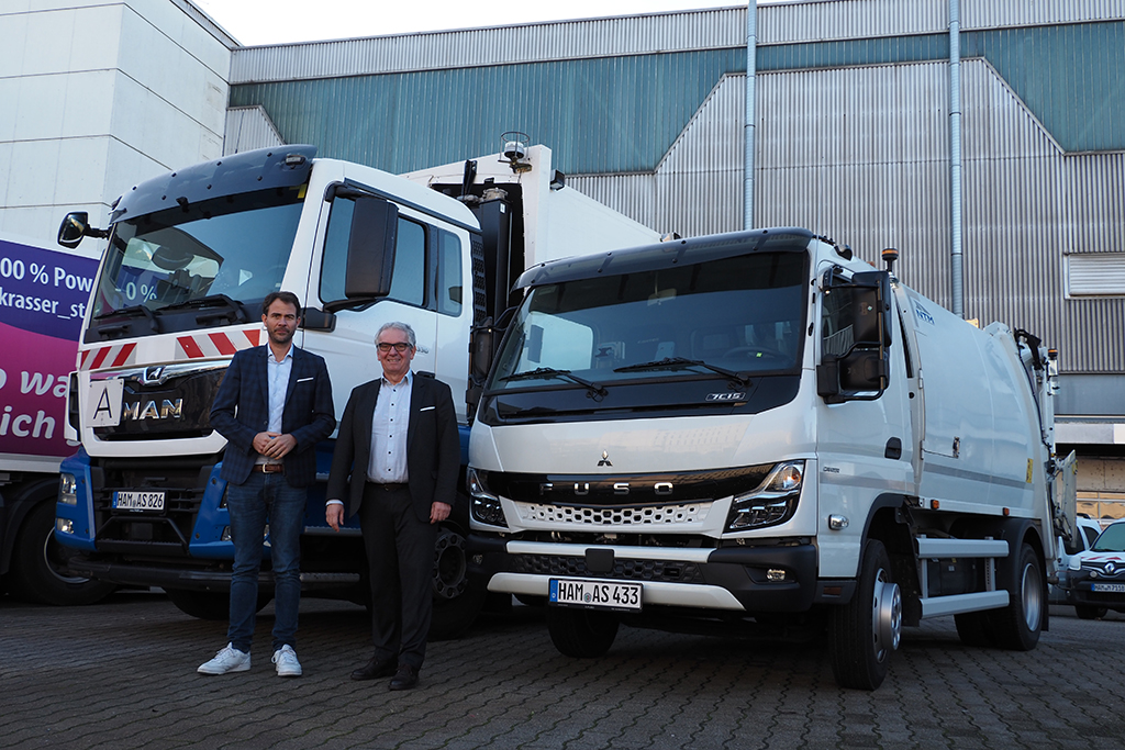 ASH-Betriebsleiter Robert Reminghorst (links) und Umweltdezernent Volker Burgard stehen vor einem Engstellenfahrzeug und einem normalen Müllfahrzeug.