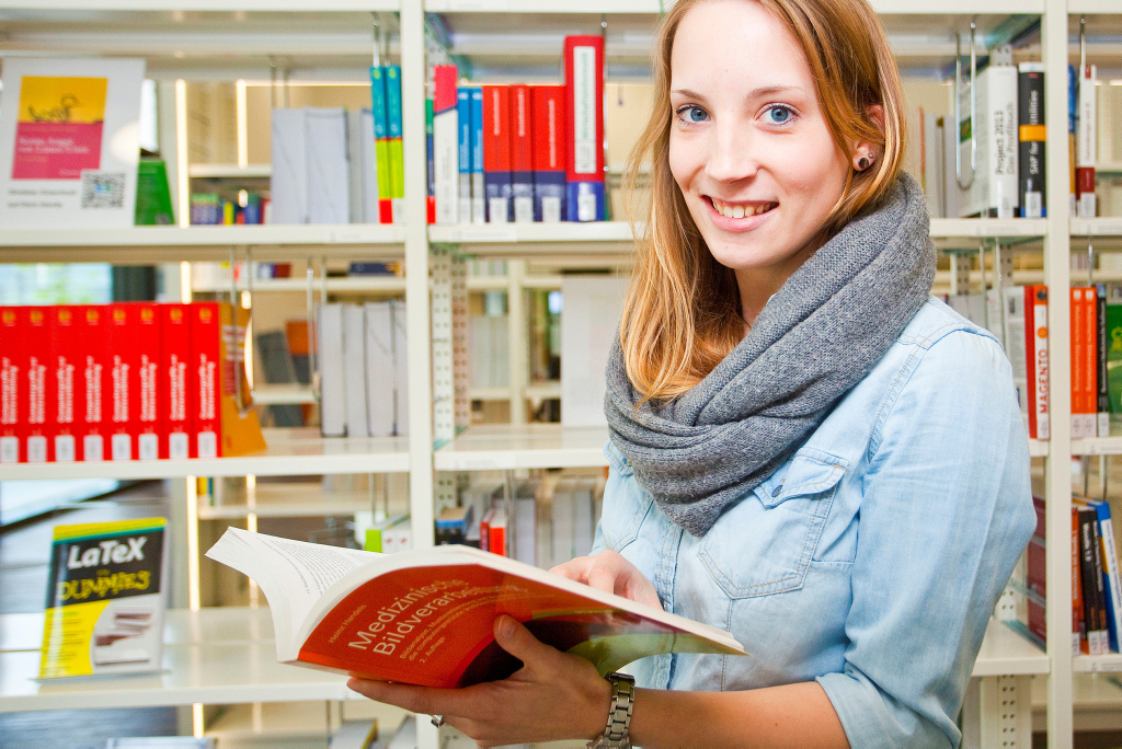Studentin in der Bibliothek der Hochschule Hamm-Lippstadt liest in einem Buch