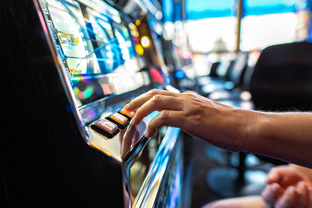 Ein Finger drückt auf einen Knopf an einem Geldspielautomaten Ein Finger drückt auf einen Knopf an einem Geldspielautomaten