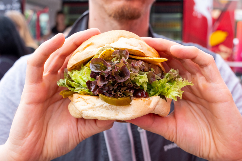 Mann hält einen veganen Burger in seinen Händen