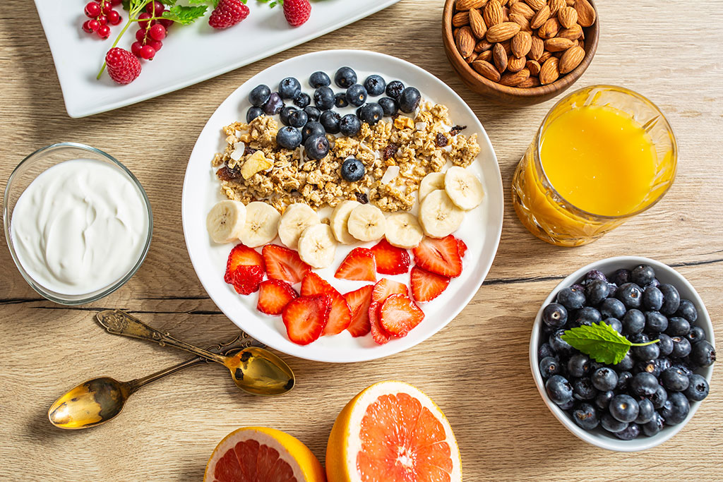 AdobeStock 292154028 Gesundes Frühstück mit Joghurt-Müsli-Heidelbeeren, Erdbeeren und Banane