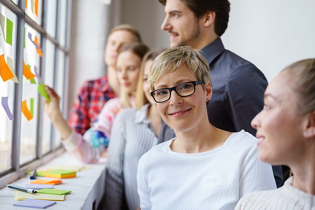 Eine lächelnde Frau arbeitet im Team in einem Workshop