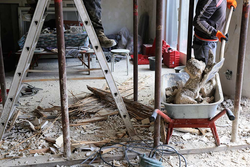 Ein Bauarbeiter lädt auf einer Baustelle Bauschutt in eine Schubkarre