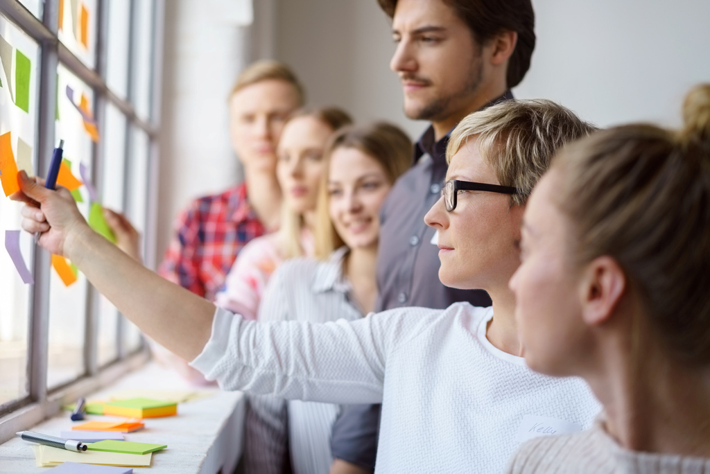 Team erarbeitet Ideen und klebt Zettel an ein Fenster Team erarbeitet Ideen und klebt Zettel an ein Fenster