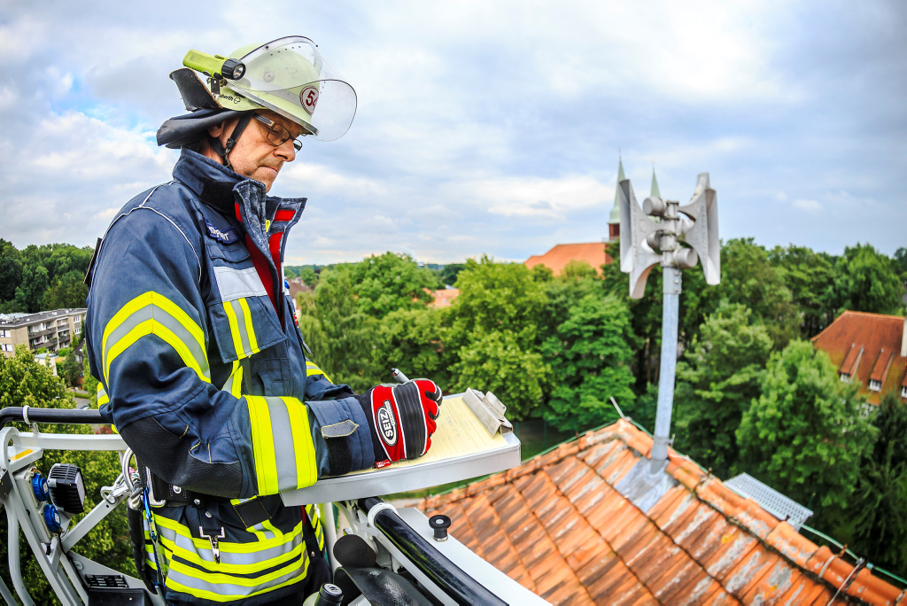 Ein Feuerwehrmann prüft eine Sirene auf dem Dach eines Hauses
