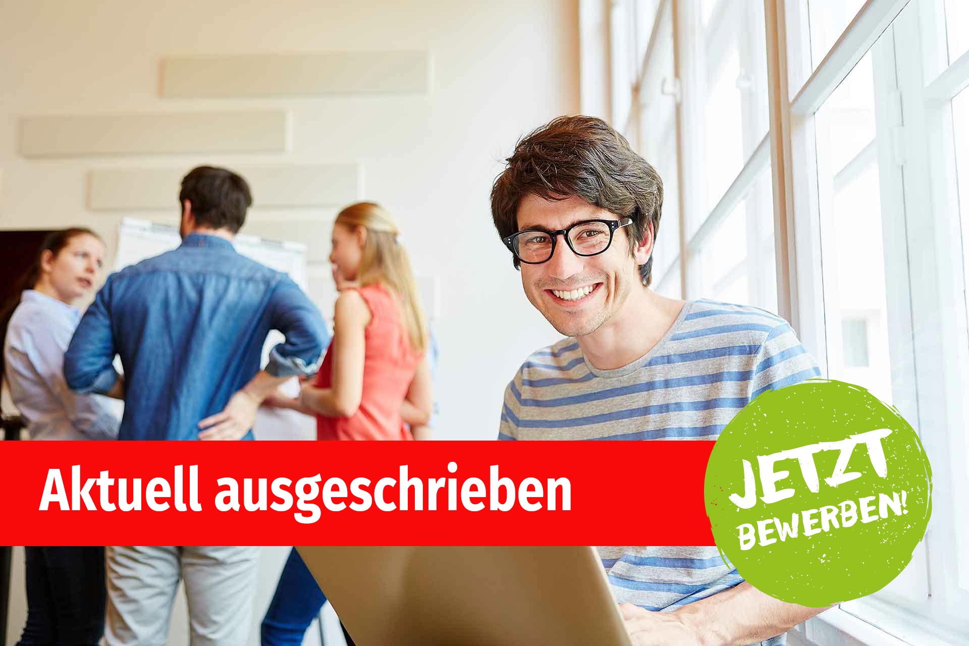 Ein Student am Laptop vor einer Gruppe vom Menschen Ein Student am Laptop vor einer Gruppe vom Menschen
