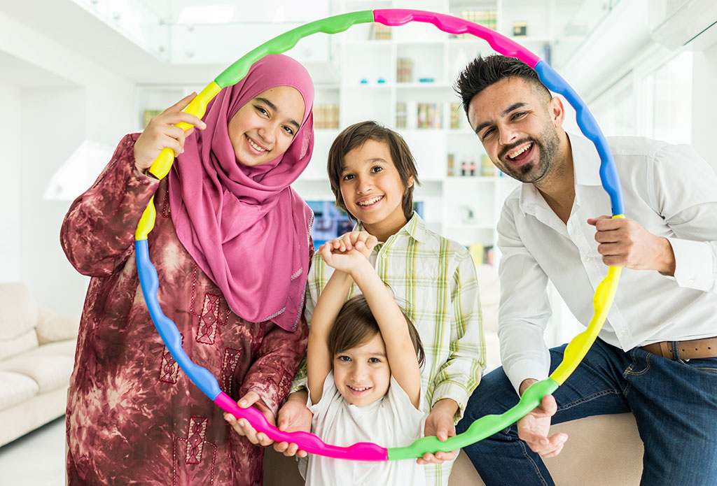 Arabische muslimische, moderne Familie schaut lachend durch einen Hula Hoop-Reifen