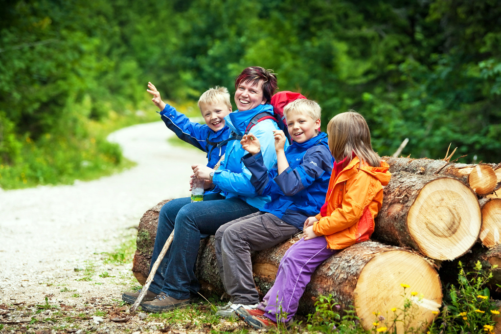 Familie bei kleiner Pause auf Baumstämmen im Wald Familie bei kleiner Pause auf Baumstämmen im Wald