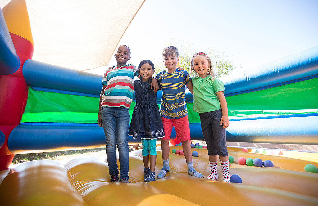 Vier Kinder stehen in einer Hüpfburg und halten sich im Arm