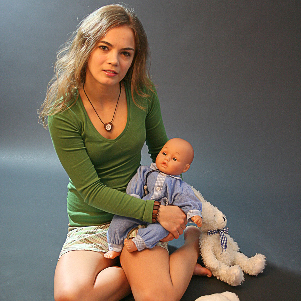 Junge Frau mit Puppe und Plüschtieren