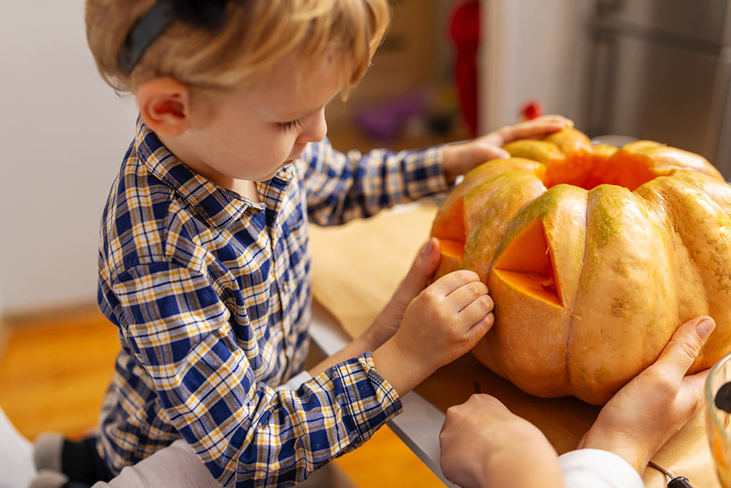 Ein kleiner Junge schnitzt einen Halloweenk&uuml;rbis
