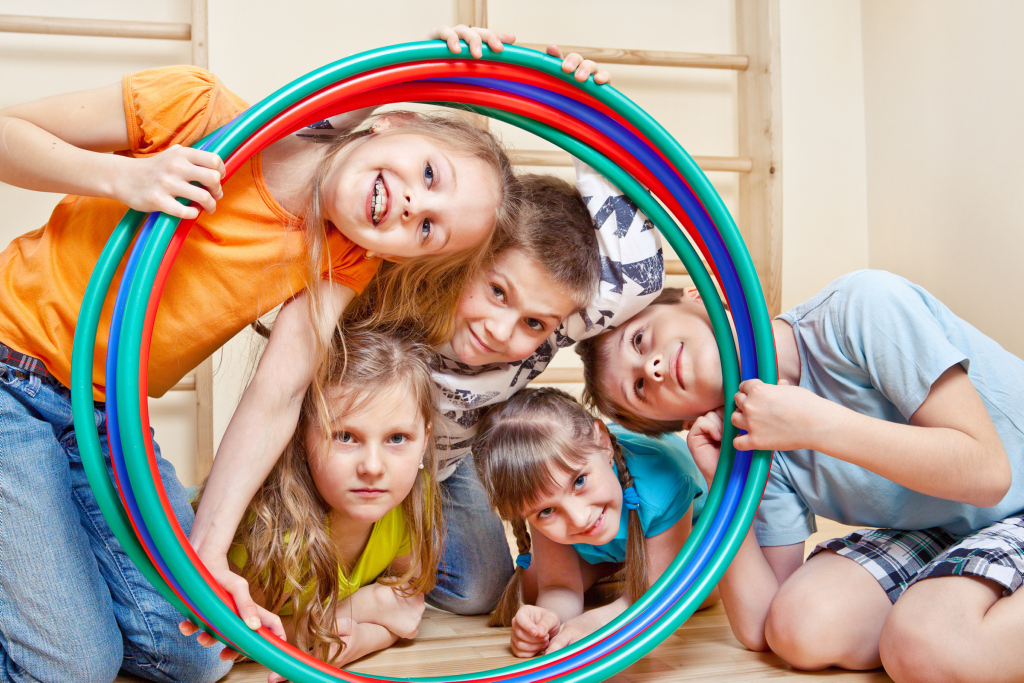 Lachende Kinder schauen durch einen Hula Hoop-Reifen Lachende Kinder schauen durch einen Hula Hoop-Reifen