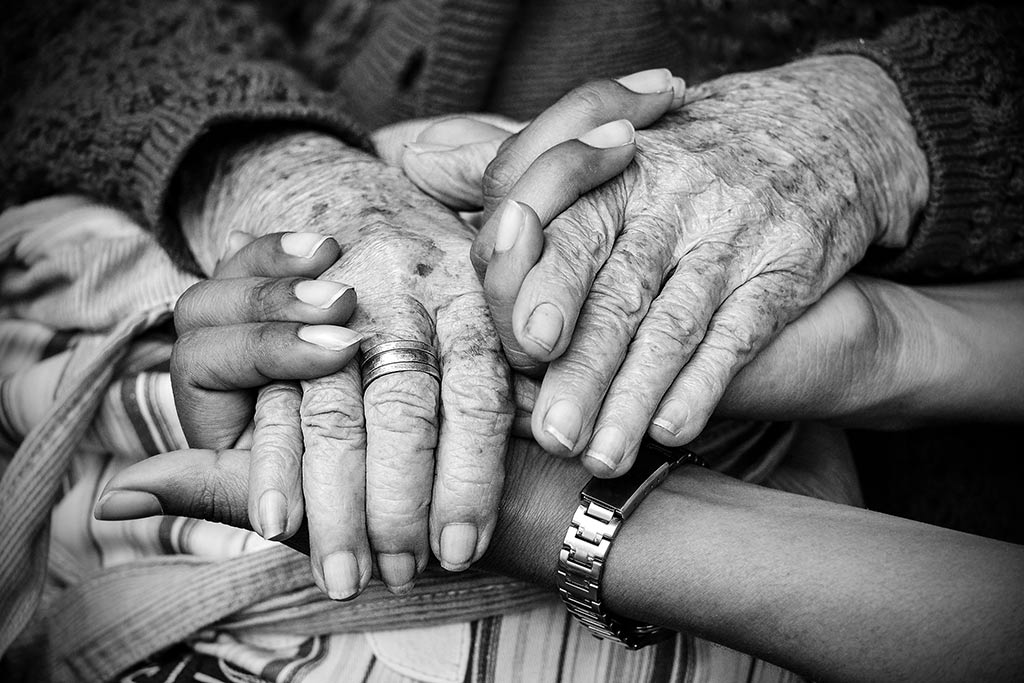 Hände einer älteren und einer jüngeren Person greifen ineinander