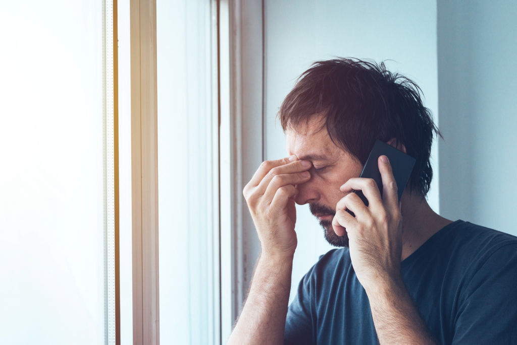 ein frustrierter Mann mit Smartphone am Ohr ein frustrierter Mann mit Smartphone am Ohr