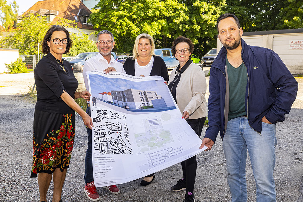 Eine Gruppe von Personen hält eine Plan zum Neubau der Kita Wolkenwunder