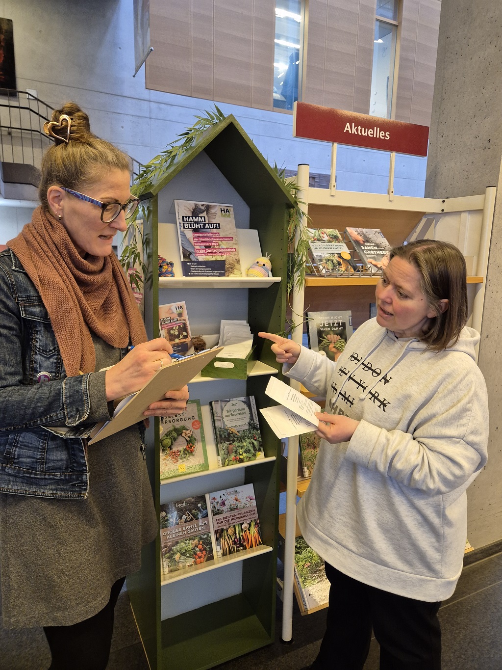 Bild zeigt zwei Personen vor einem Regal, die sich &uuml;ber Saatgut unterhalten