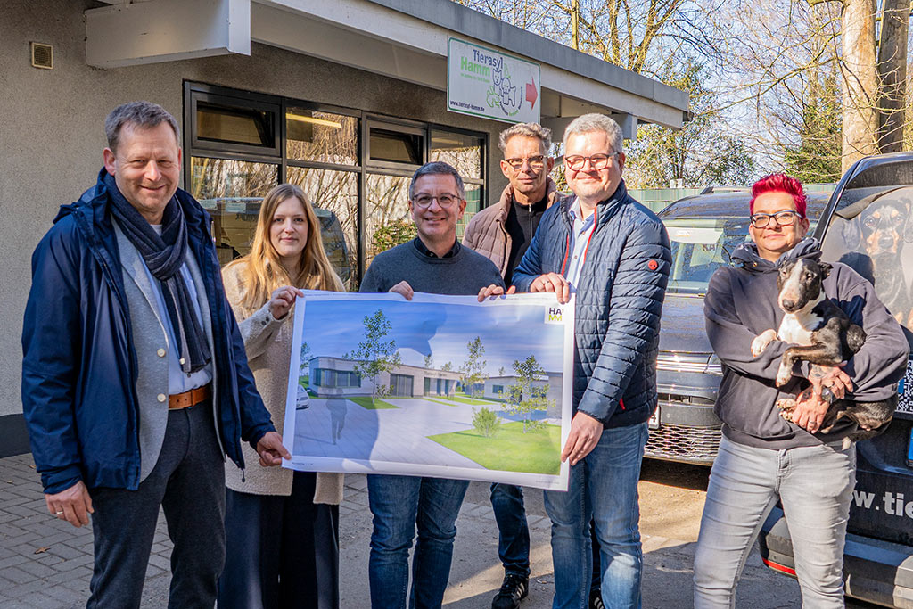 Eine Gruppe von Personen zeigt auf einem Plakat eine Zeichnung des neue Geb&auml;udes des Tierasyls