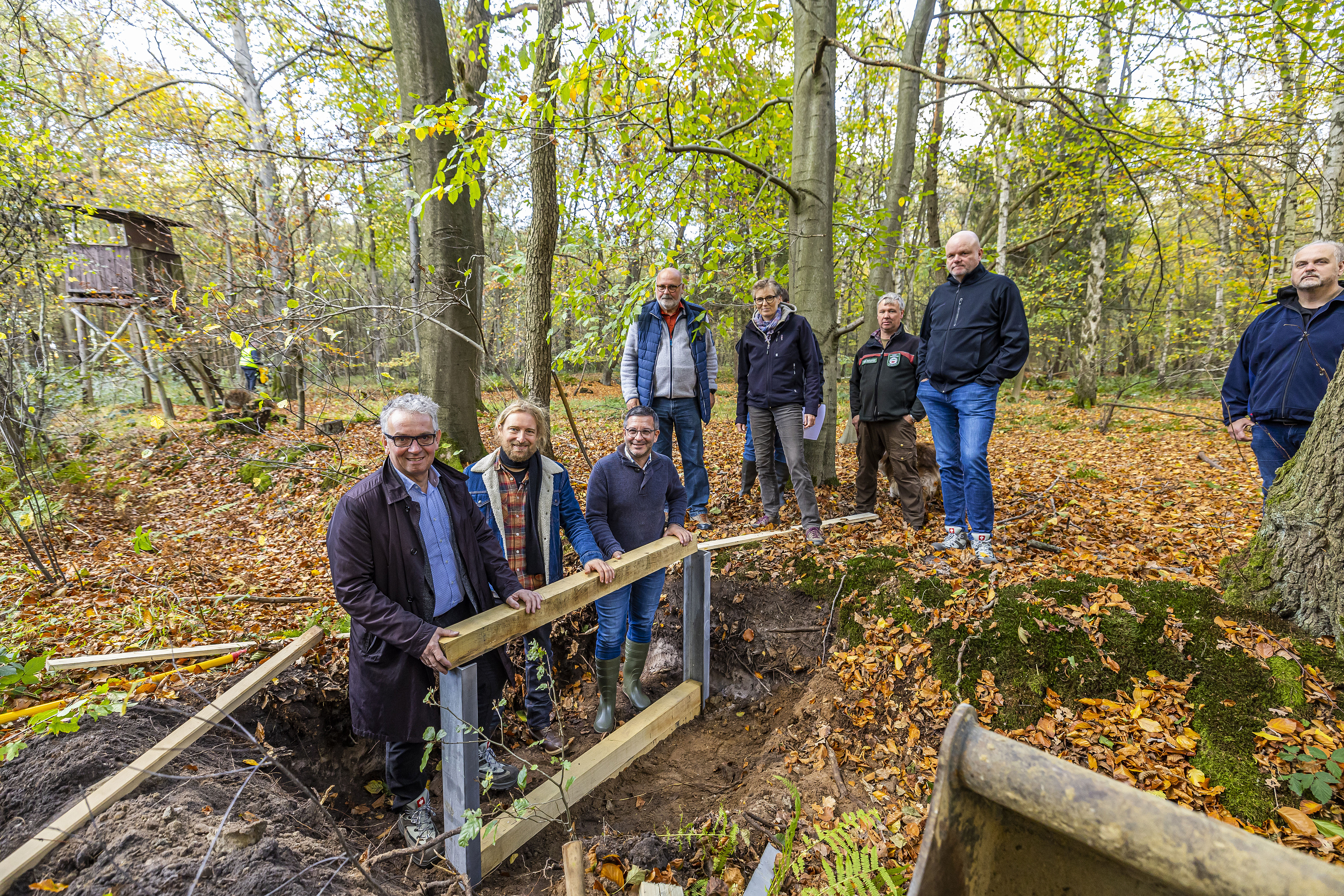 Das Foto zeigt den OB Marc Heter und andere Beteiligte beim Pressetermin zum Grabenverschluss im Wald in Sandbochum.