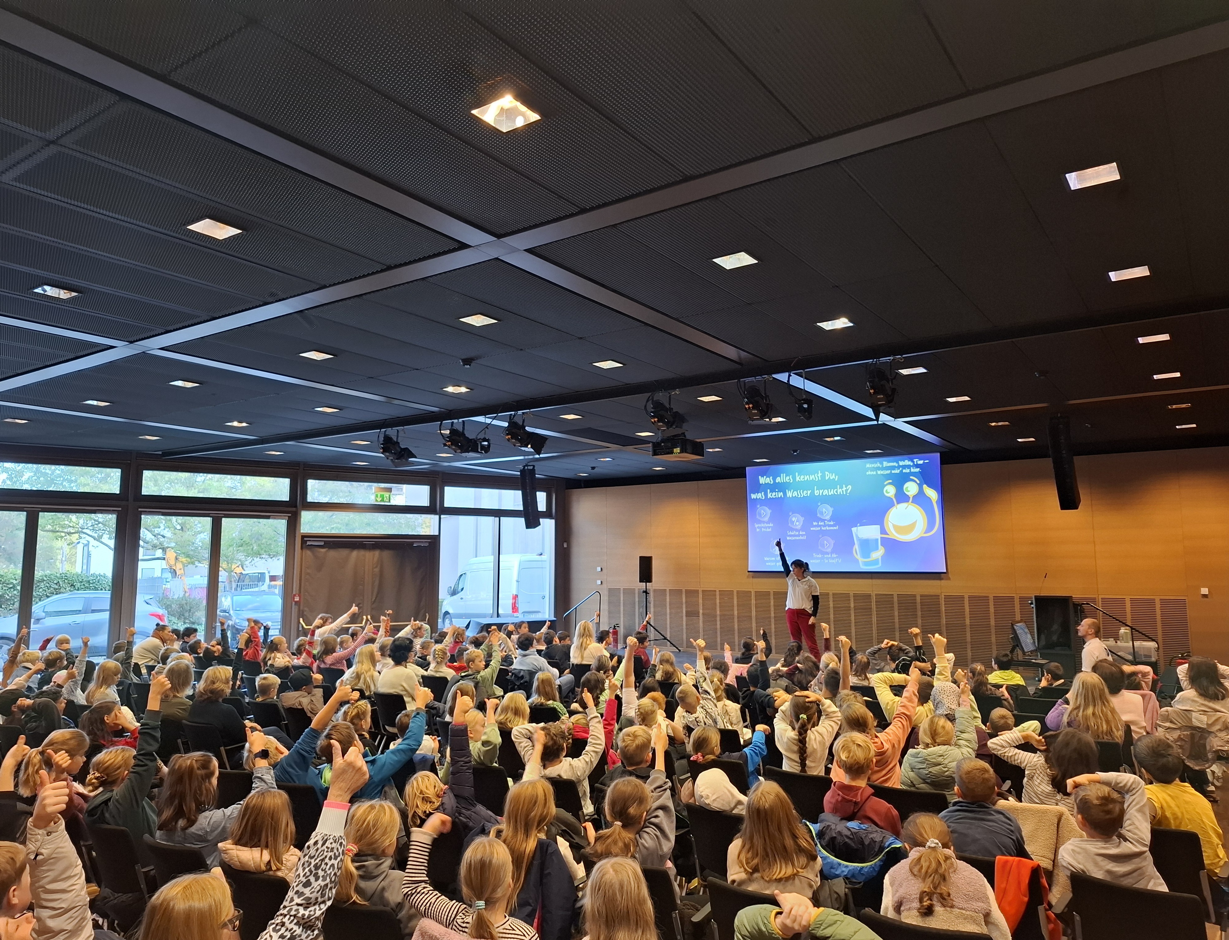 B&uuml;hnenprogramm der interaktiven Theatergruppe FS Infotainment im Gerd-Bucerius-Saal der Stadt Hamm. Zu sehen sind Kinder, die aufzeigen und sich am Programm zum Thema Trinkwasserschutz beteiligen.