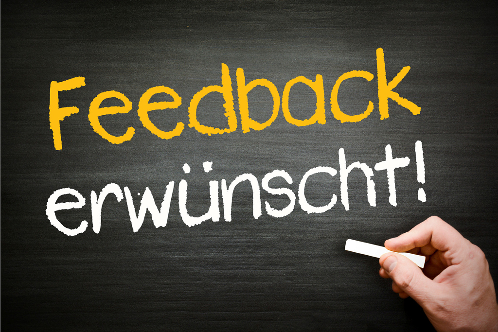 Mit Kreide auf einer Tafel geschrieben: "Feedback erwünscht!"