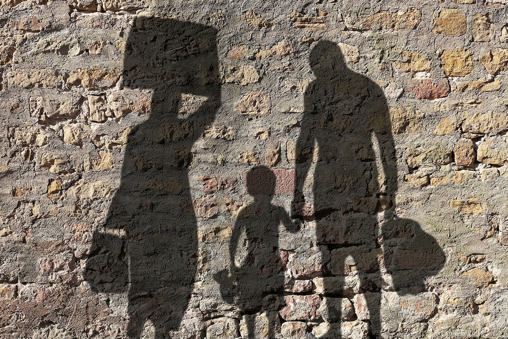 Schatten einer Flüchtlingsfamilie auf einer Mauer
