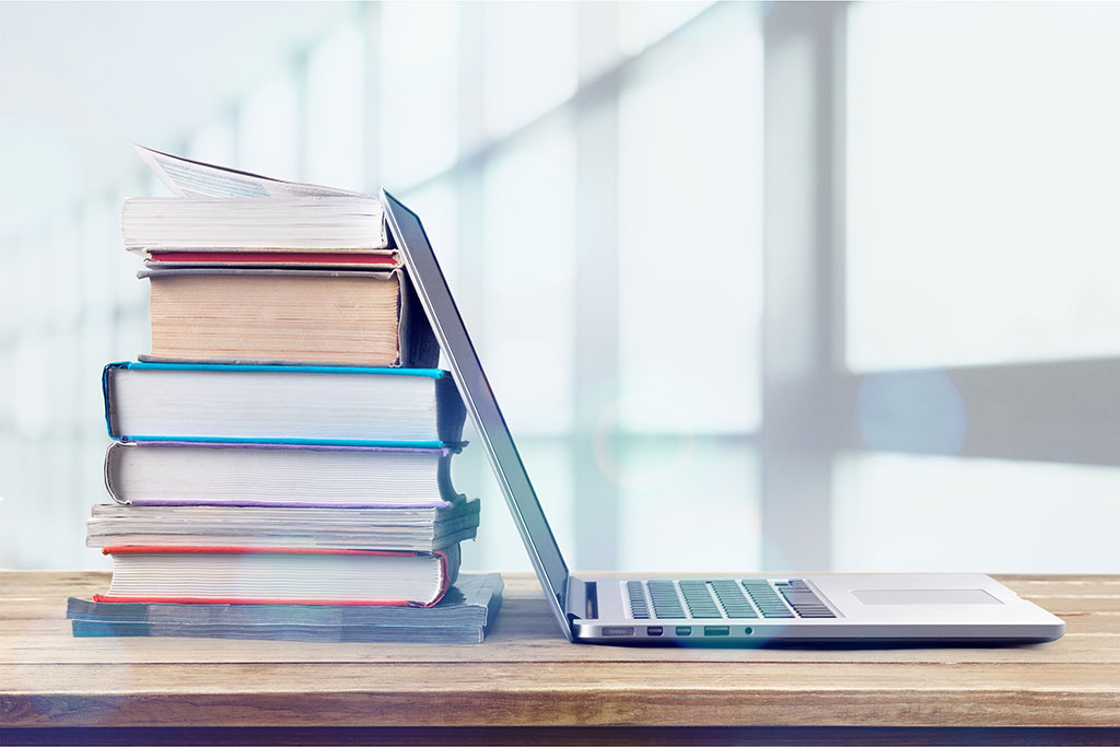 AdobeStock 242832455 Ein Stapel Bücher mit einem Laptop