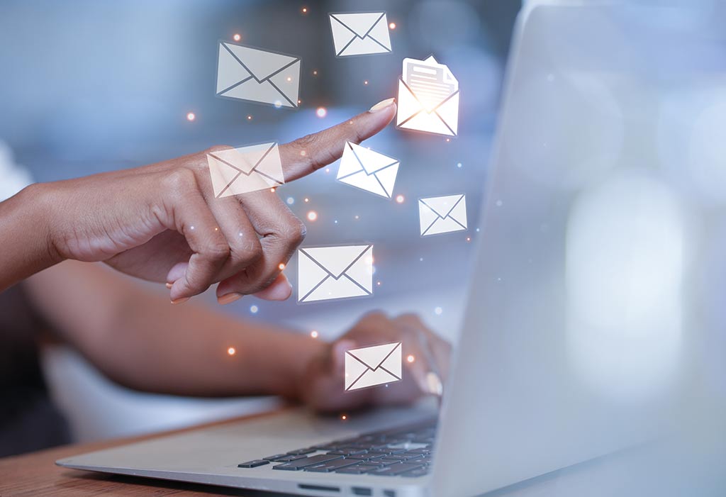Eine Hand zeigt auf E-Mail-Symbole, die vor einem Laptop schweben