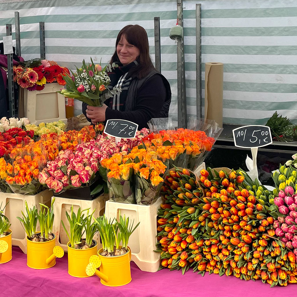 Eine Verkäuferin am Wochenmarktstand von Blumen Hoffmann