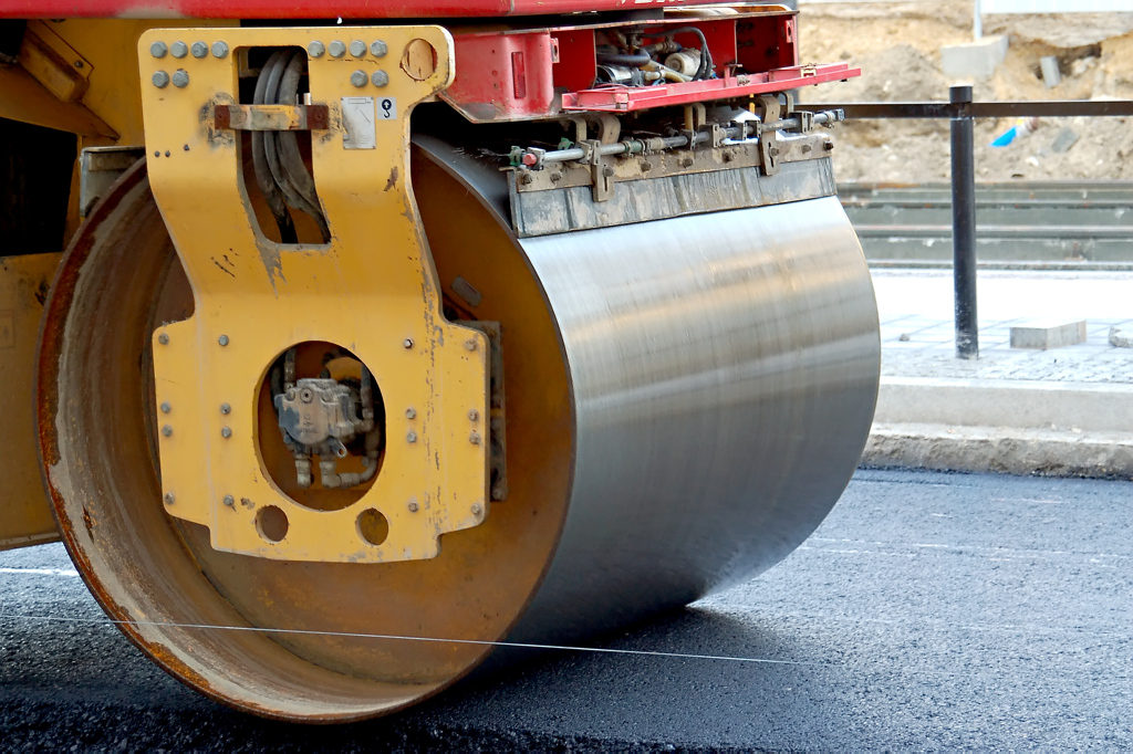 Eine Stra&szlig;enwalze planiert frischen Asphalt