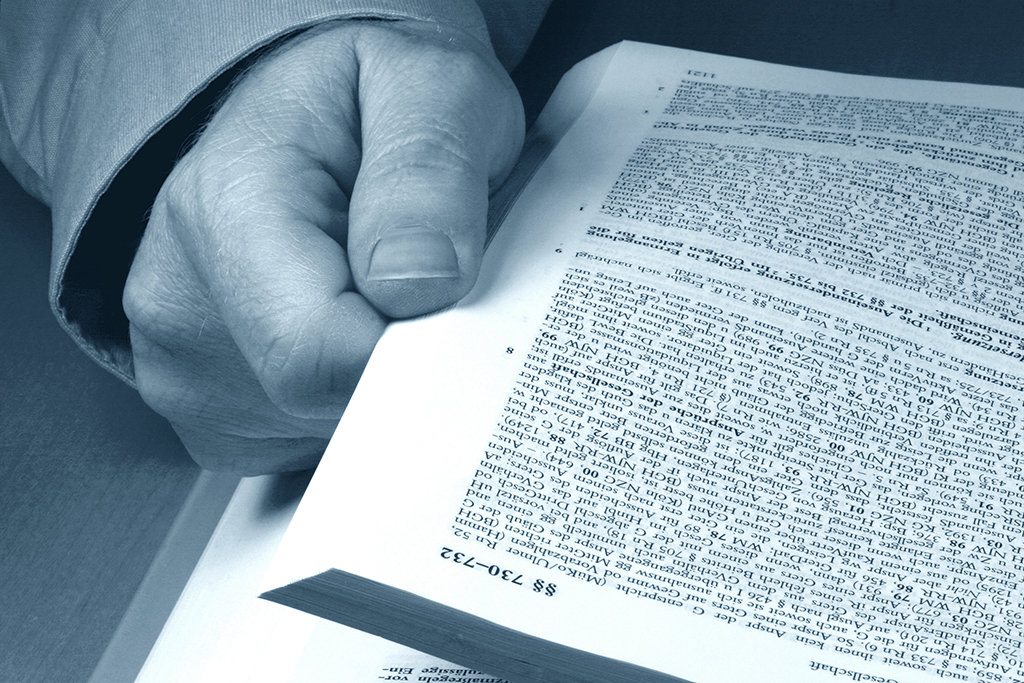 Ein Mann blättert in einem Gesetzbuch Ein Mann blättert in einem Gesetzbuch