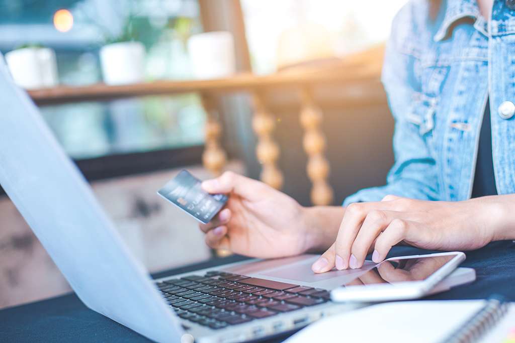 Eine junge Frau hält eine Kreditkarte in der Hand um online zu bezahlen Eine junge Frau hält eine Kreditkarte in der Hand um online zu bezahlen