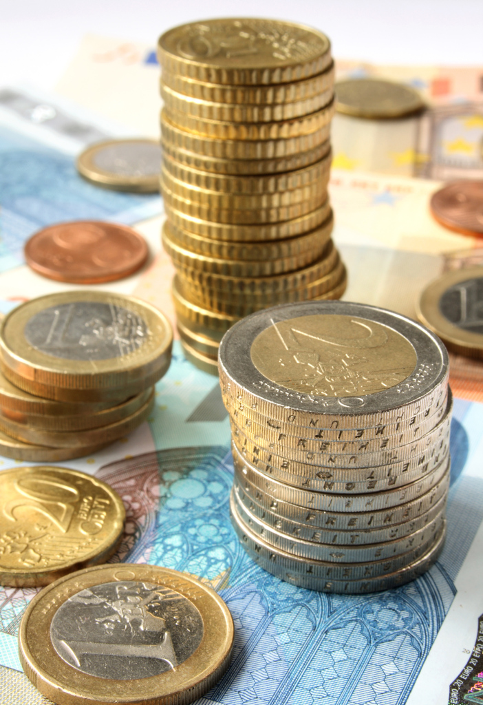 Verschiedene Stapel von Geldm&uuml;nzen, die auf Geldscheinen stehen