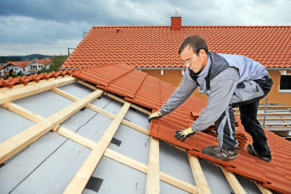 Ein Facharbeiter deckt ein Dach ein